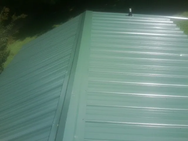 New green metal panels meeting at the ridge of a roof — Flat Roof Repair work by our crew in Tidewater