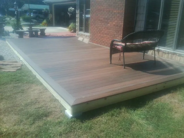 New wood deck and wicker chair beside a brick house in Tidewater