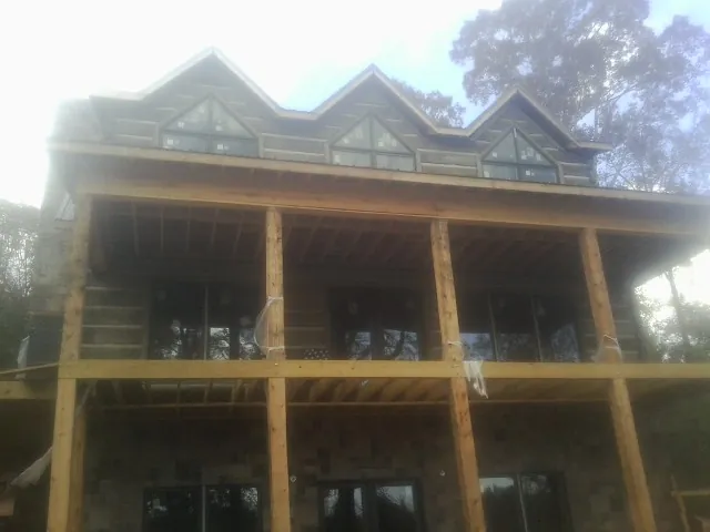 Dormers and porch framing on a large log home under construction — Roof Coating work by our crew in Tidewater