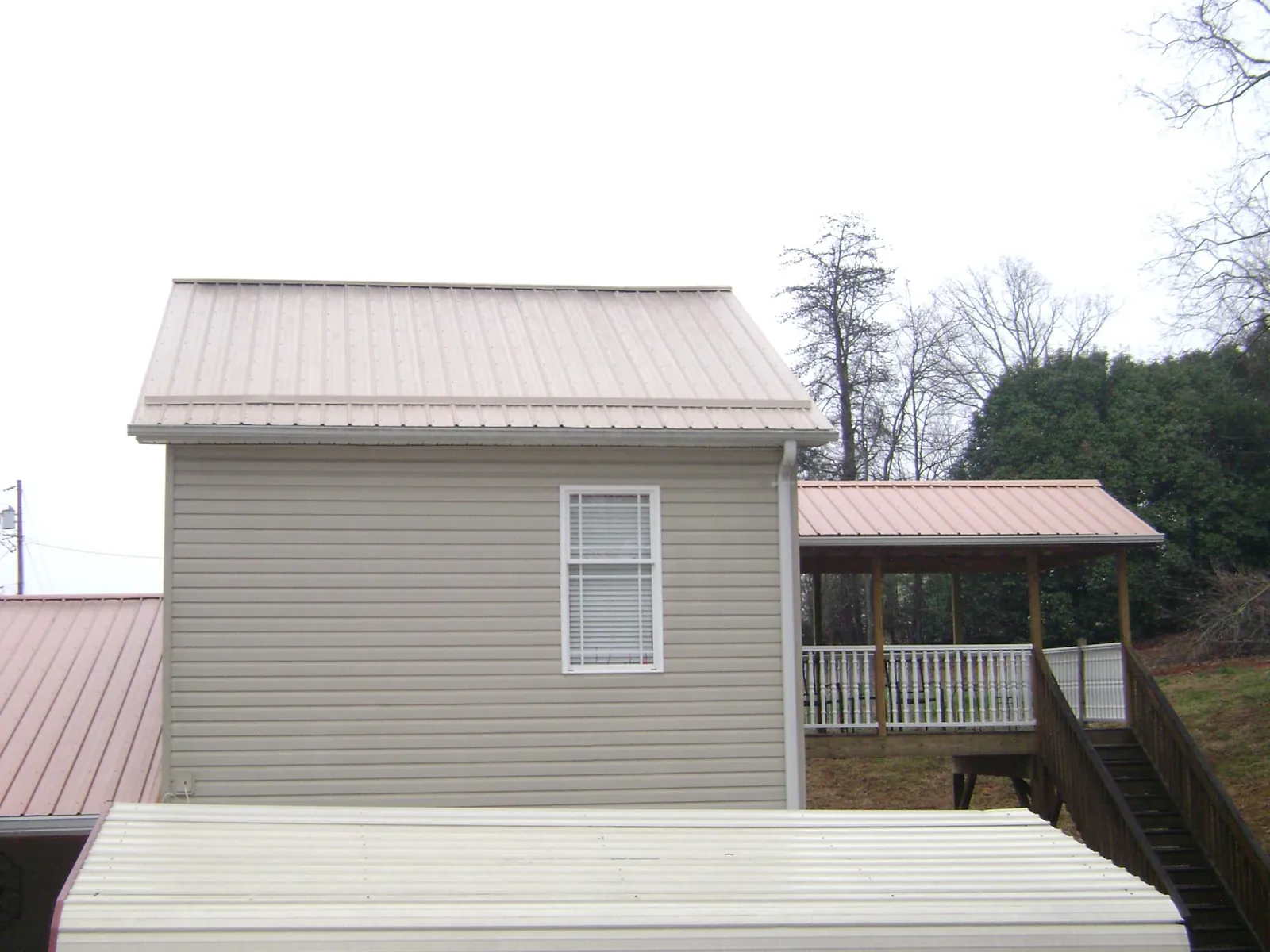 Tan metal roofs on a two story addition and attached porch, from a Roof Replacement job in Tidewater
