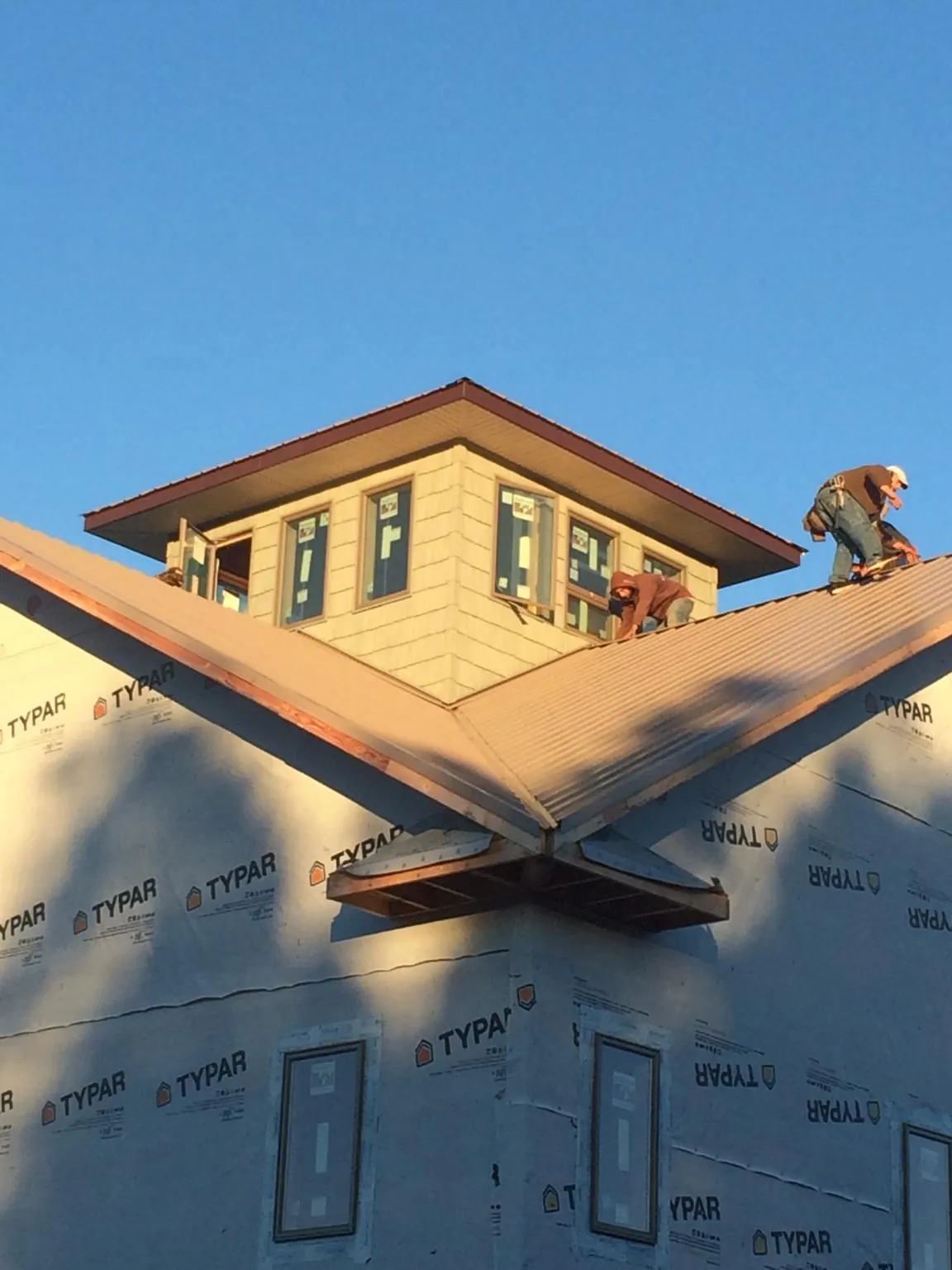 Roofers working around a rooftop cupola on a new metal roof at sunset — Roof Waterproofing in Tidewater by Roofing Brothers